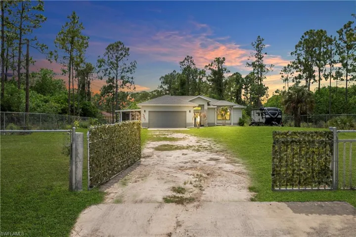 Modern ranch-style residence featuring a gray shingle roof, attached two-car garage, and a chain-link fence