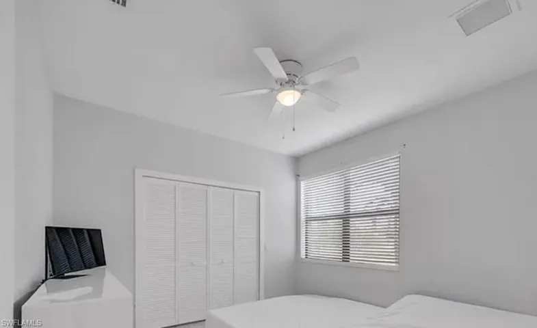 Bright interior space featuring a ceiling fan with integrated lighting, a window with horizontal blinds, and bi-fold louvered closet doors