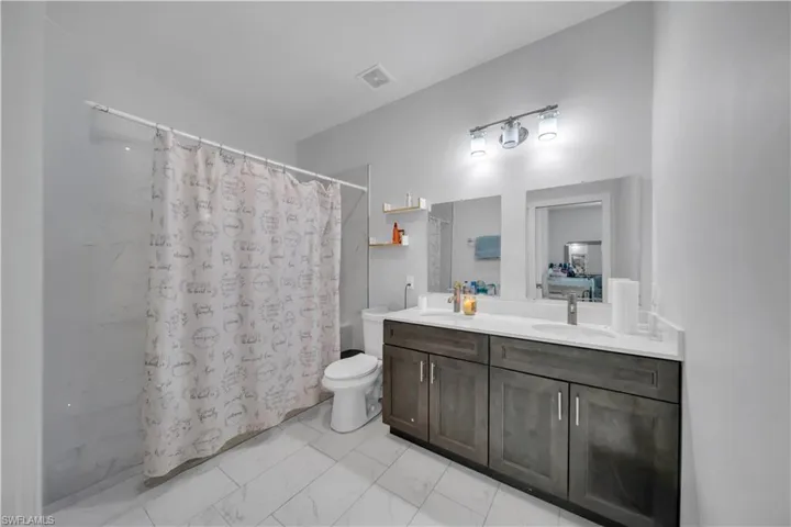 Bathroom featuring a dual vanity with a white countertop and wood-finish cabinetry