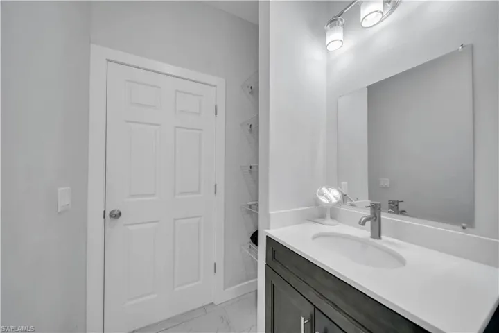 Bathroom vanity with a white countertop, undermount sink, and brushed nickel faucet