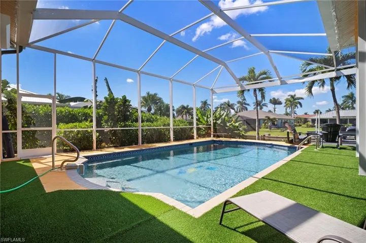 Swimming pool with a sunroom, a lanai, a patio area, and a yard