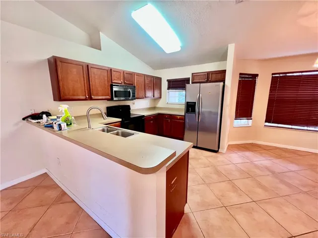 Kitchen featuring light countertops, light tile patterned floors, breakast bar, and appliances with stainless steel finishes