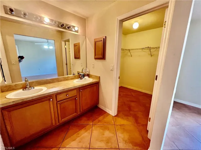 Primary bathroom with shower/ tub combo, double vanity, and a sink and walk in closet.