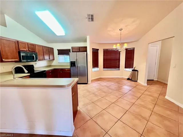Kitchen featuring light countertops, light tile patterned floors, breakast bar, and appliances with stainless steel finishes