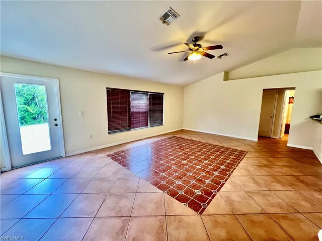 Living room featuring light tile patterned flooring with cathedral ceilings.