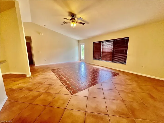Living room featuring light tile patterned flooring with cathedral ceilings.