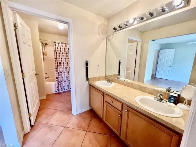 Primary bathroom with shower/ tub combo, double vanity, and a sink and walk in closet.