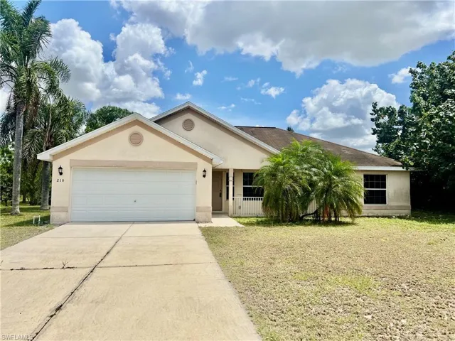 Ranch-style house with a front lawn, driveway, stucco siding, and a garage