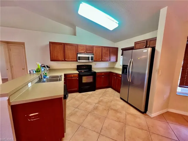 Kitchen featuring light countertops, light tile patterned floors, breakast bar, and appliances with stainless steel finishes