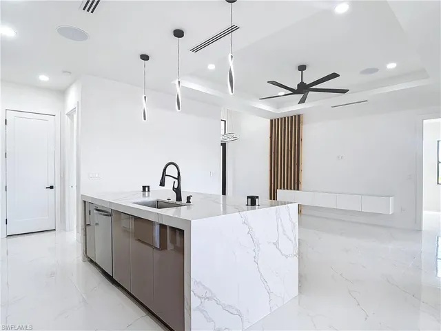Kitchen with a spacious island, sink, hanging light fixtures, and a tray ceiling