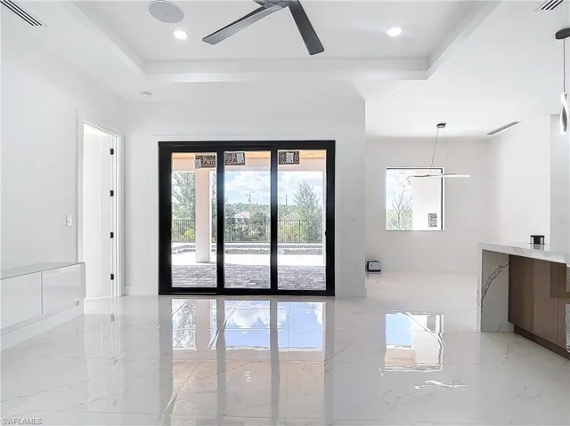 Empty room with ceiling fan and a tray ceiling