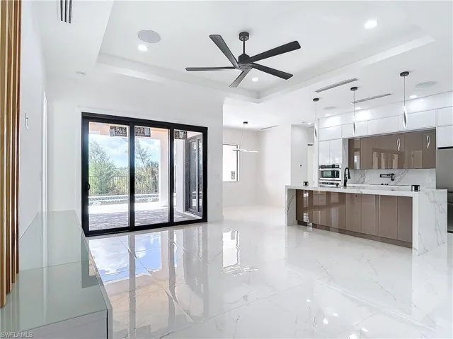 Kitchen with a large island, pendant lighting, a tray ceiling, and sink