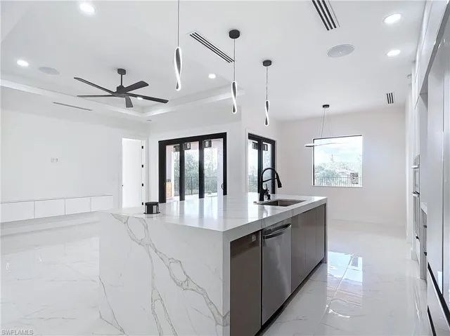 Kitchen with dishwasher, french doors, hanging light fixtures, a large island, and sink