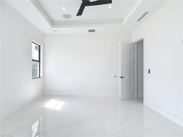Spare room with ceiling fan and a tray ceiling