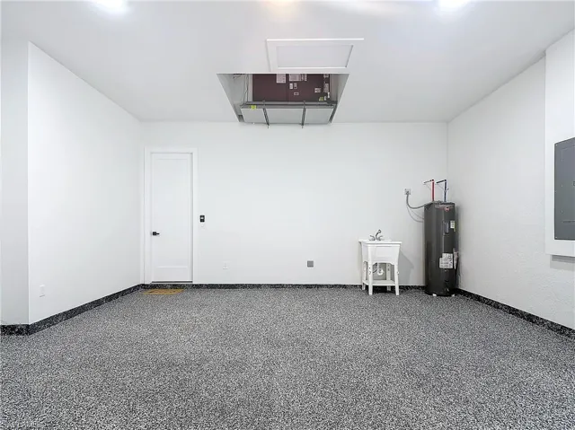 Garage featuring electric water heater and electric panel