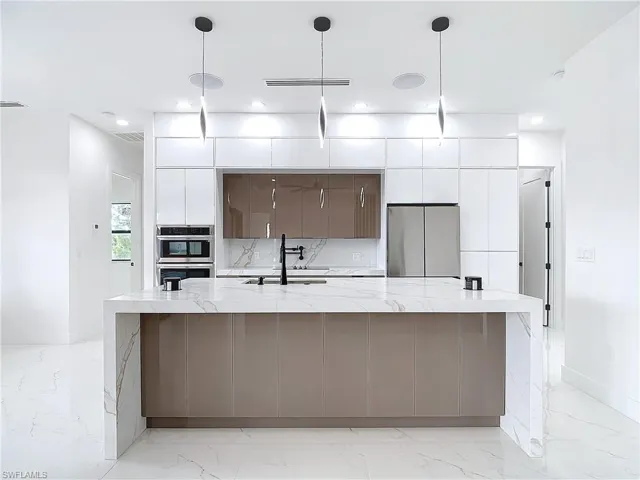 Kitchen with a large island with sink, sink, and hanging light fixtures
