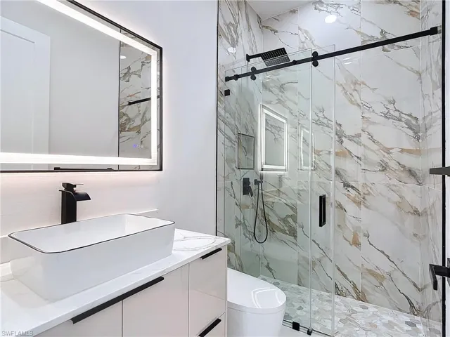 Bathroom featuring vanity, walk in shower, and toilet
