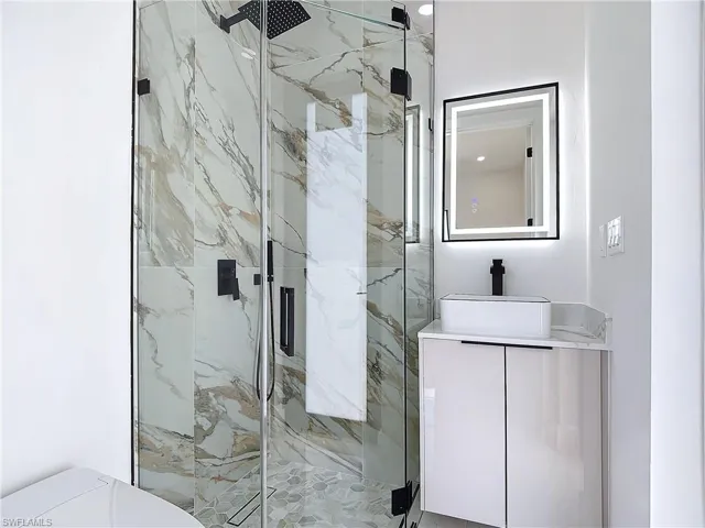 Bathroom featuring vanity, an enclosed shower, and toilet