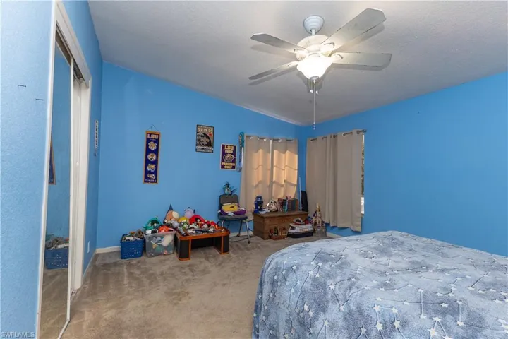 Carpeted bedroom with a textured ceiling and a ceiling fan