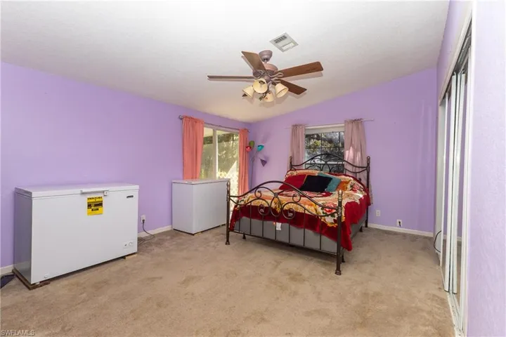 Bedroom with white refrigerator, light carpet, a ceiling fan, and lofted ceiling