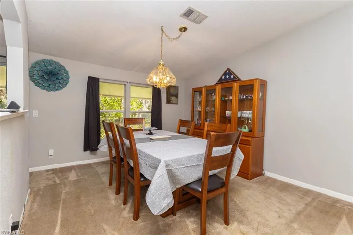 Dining room featuring light carpet, vaulted ceiling, and a chandelier