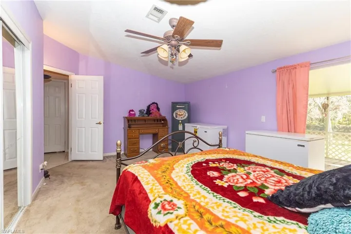 Bedroom with light carpet, a ceiling fan, and vaulted ceiling