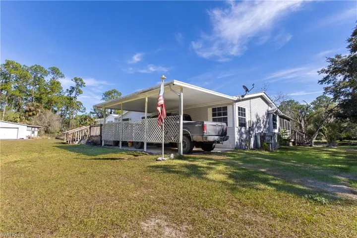 Back of property featuring a yard, a carport, and stairs