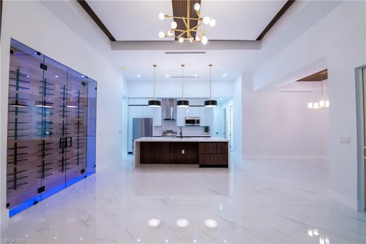 Kitchen featuring a large island, decorative light fixtures, stainless steel appliances, and a chandelier