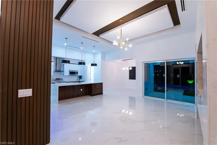 Kitchen with pendant lighting, sink, a center island, stainless steel appliances, and an inviting chandelier