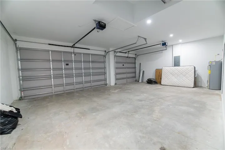 Garage featuring a garage door opener, electric water heater, and electric panel