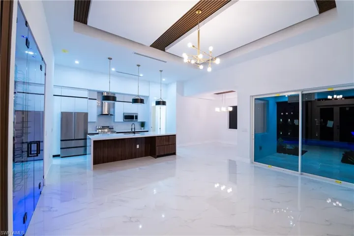 Kitchen with decorative light fixtures, sink, a large island, stainless steel appliances, and wall chimney exhaust hood
