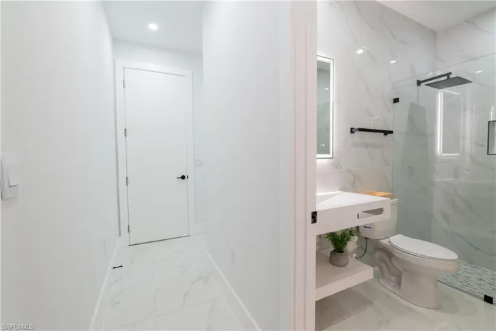 Bathroom with vanity, a shower with shower door, and toilet