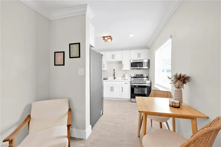 Kitchen featuring appliances with stainless steel finishes, light countertops, ornamental molding, and white cabinetry