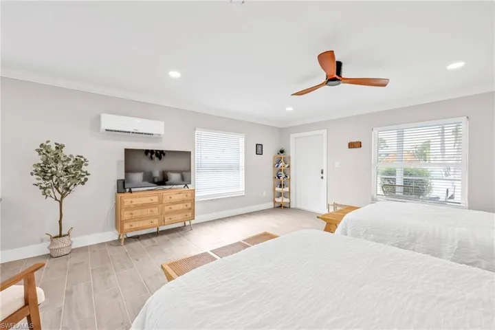 Bedroom featuring wood tiled floors, crown molding, ceiling fan, recessed lighting, and a wall mounted air conditioner