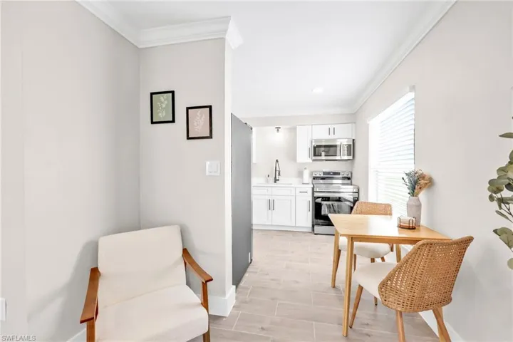Kitchen featuring white cabinetry, crown molding, light countertops, stainless steel appliances, and wood finish floors