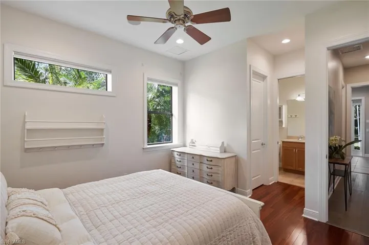 Bedroom featuring ceiling fan, ensuite bathroom, sink, and dark wood-type flooring