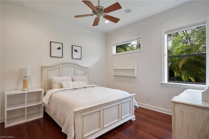 Bedroom featuring multiple windows, ceiling fan, and dark hardwood / wood-style flooring