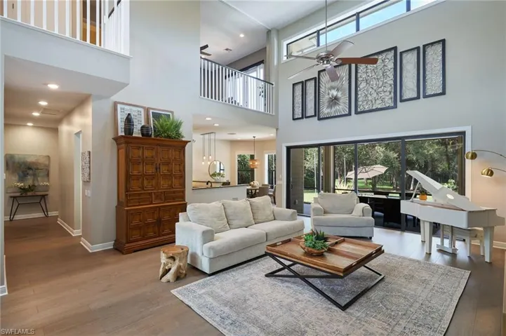 Living room with ceiling fan, hardwood / wood-style flooring, plenty of natural light, and high ceilings