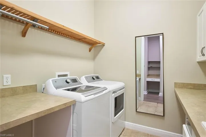 Laundry area with cabinets, utility sink light tile floors, and washer and dryer