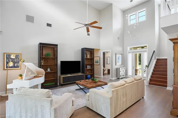 Living room with a towering ceiling, ceiling fan, and hardwood / wood-style floors
