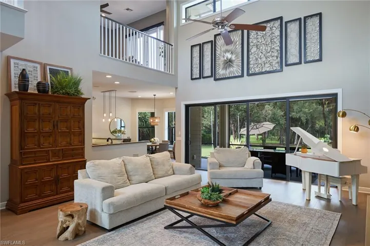 Living room featuring ceiling fan, light wood-type flooring, and a towering ceiling