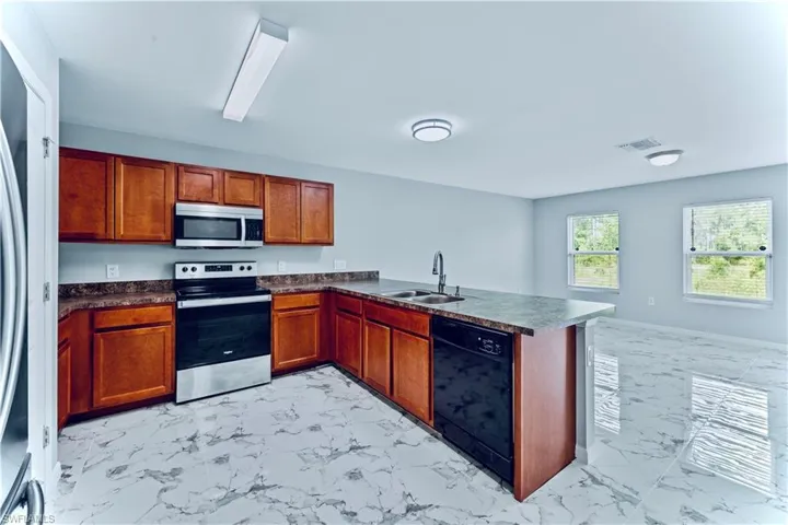 Kitchen featuring appliances with stainless steel finishes, sink, light tile flooring, and kitchen peninsula
