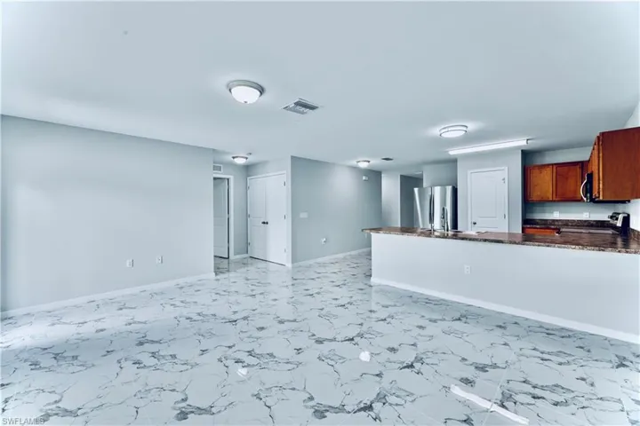 Kitchen with light tile flooring, kitchen peninsula, stainless steel appliances, dark stone countertops, and sink