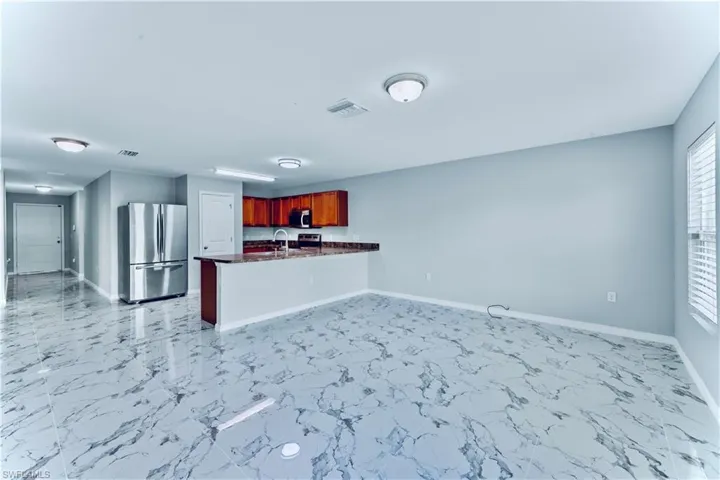 Kitchen with sink, kitchen peninsula, light tile flooring, and appliances with stainless steel finishes