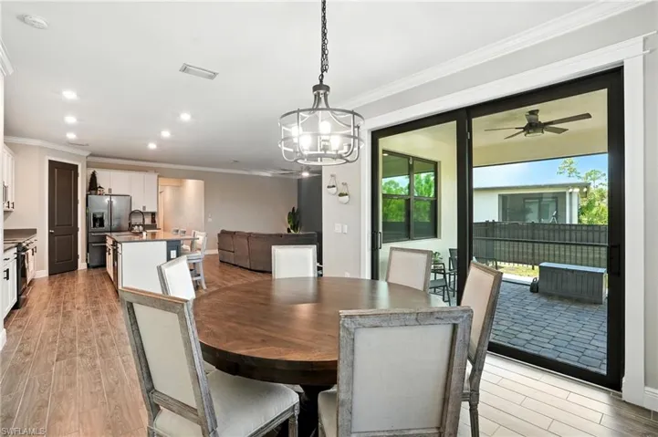Dining room with ornamental molding, light wood finished floors, recessed lighting, a ceiling fan, and a chandelier