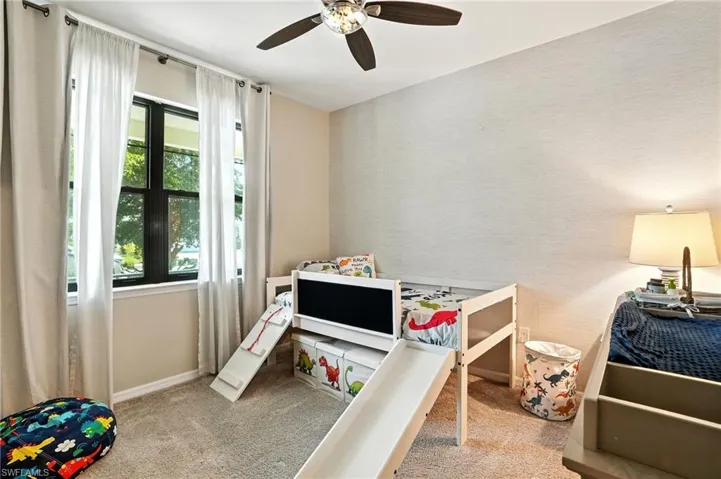 Bedroom featuring light colored carpet, ceiling fan, and wallpapered walls