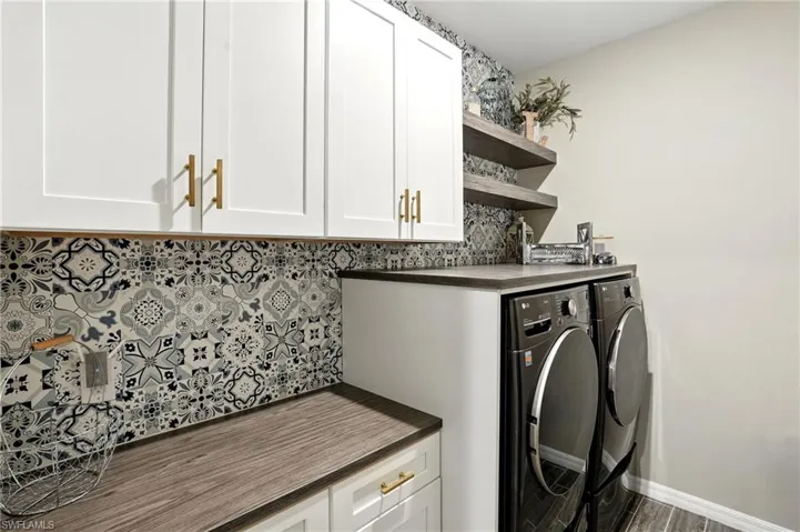 Washroom featuring washer and clothes dryer, cabinet space, and wood finished floors