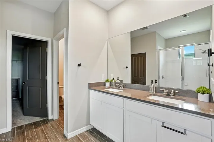 Full bathroom with a shower stall, wood finish floors, and double vanity