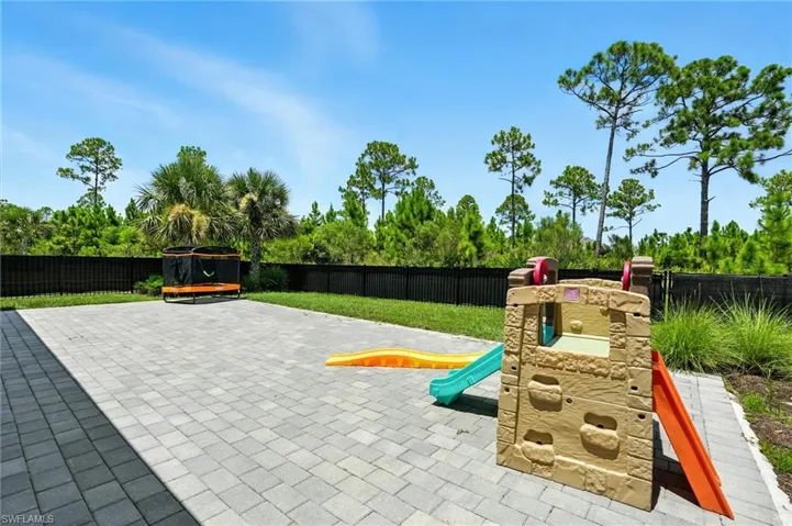 View of playground with a fenced backyard, a patio area, and a trampoline