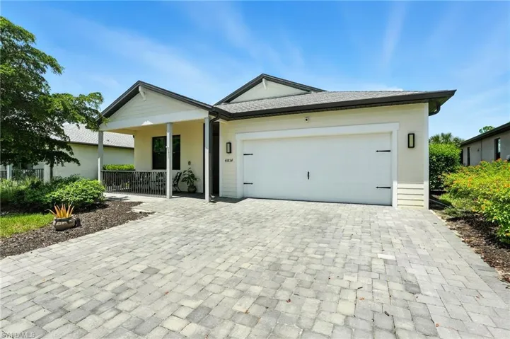 Ranch-style home featuring an attached garage, decorative driveway, and covered porch